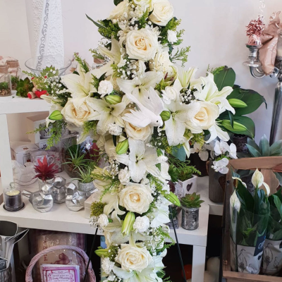 Tranquil Cross Tribute - A peaceful and elegant cross-shaped arrangement, predominantly white with soft green accents, symbolising serenity and remembrance. This tribute offers comfort and conveys deep sympathy.