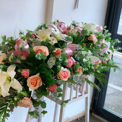 Rose Garden Casket Spray - A stunning casket spray featuring an abundance of roses in soft pink and peach tones, complemented by lush greenery. This arrangement offers a gentle and elegant expression of love and farewell.