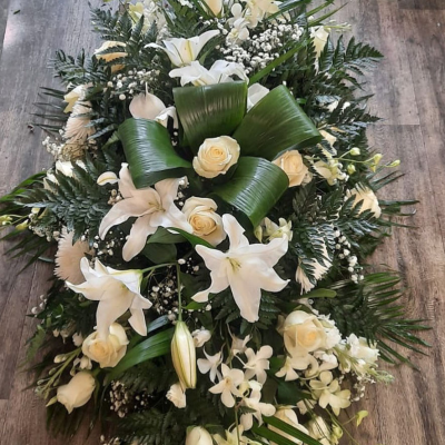 Classic White Elegance - A timeless arrangement of white lilies and roses, set against a backdrop of rich green foliage. This classic design represents purity and eternal peace, making it a fitting tribute.