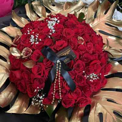 Eternal Love Rose Bouquet - A captivating and luxurious bouquet, this arrangement features a stunning display of deep red roses, symbolizing deep love and passion. The roses are arranged in a circular formation and accented with elegant golden leaves. The addition of a black ribbon and delicate beads elevates the romantic theme, making it an ideal expression of eternal love and devotion.