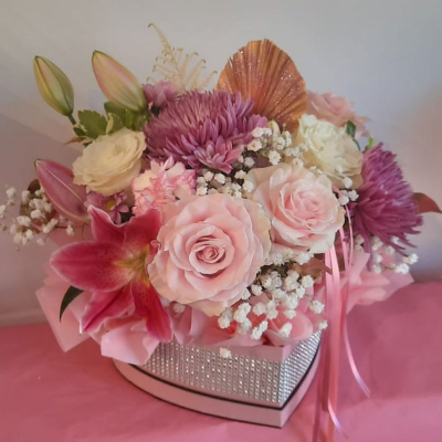 Sweetheart Blossom Box - A charming heart-shaped arrangement filled with a delightful mix of pink roses, lilies, and chrysanthemums. Accented with delicate baby’s breath and golden leaves, this design is perfect for expressing love and affection.