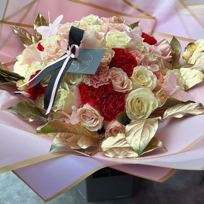 Romantic Radiance Bouquet - A vibrant mix of red and white roses, carnations, and golden leaves, arranged in a circular formation. The contrasting colors and luxurious presentation make it an ideal gift for expressing love and admiration.